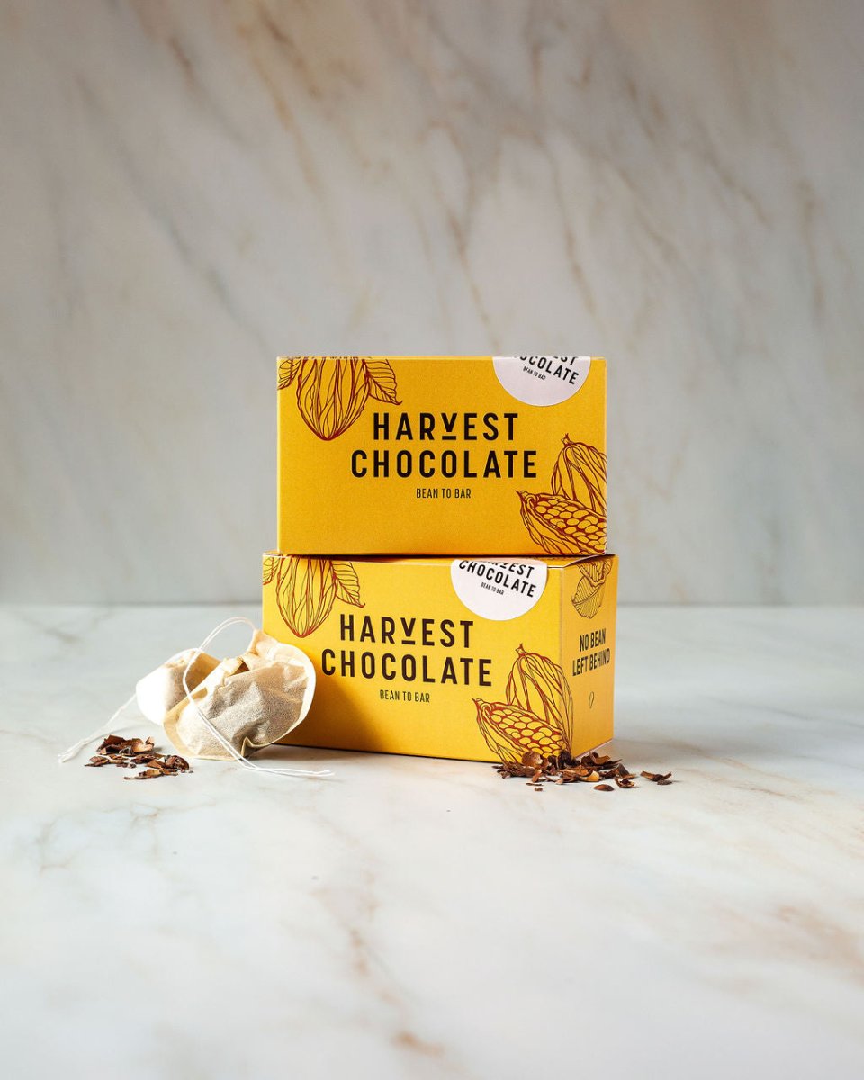 Harvest Chocolate chocolate tea box shown with cacao shells and spices on marble surface.