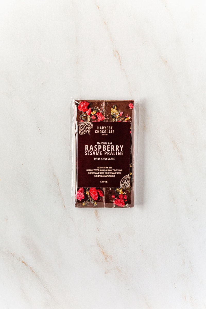 Close-up of Raspberry Sesame Praline Bar with freeze-dried raspberries and sesame praline pieces on dark chocolate.