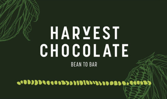 Consider adding a touch of elegance to your online shop with a stunning banner featuring "Harvest Chocolate" in bold white capital letters set against a dark green background. The phrase "Bean to Bar" is elegantly displayed below, complemented by decorative leaves in the top left and bottom right corners. A line of green cocoa beans runs horizontally across the bottom for an added flair. Don't forget to explore our Harvest Chocolate Email Gift Card today!