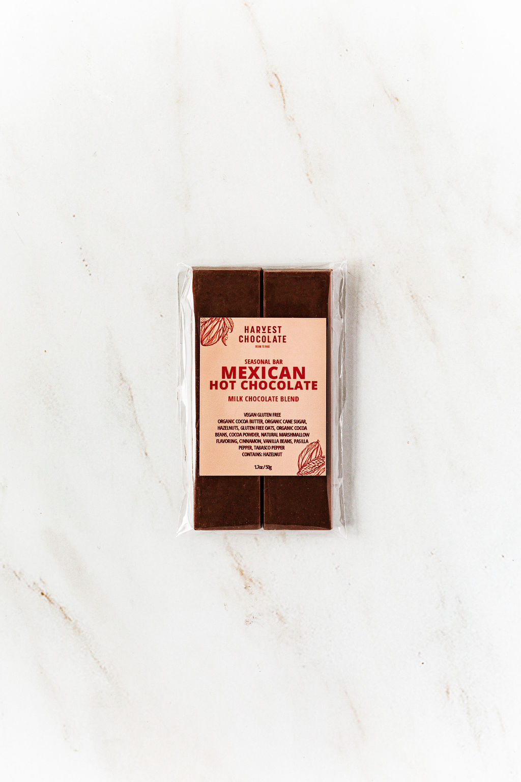 The Harvest Chocolate Special Edition Mexican Hot Chocolate features a milk chocolate blend with hints of hazelnuts, sealed in detailed packaging, resting on a light marble surface.